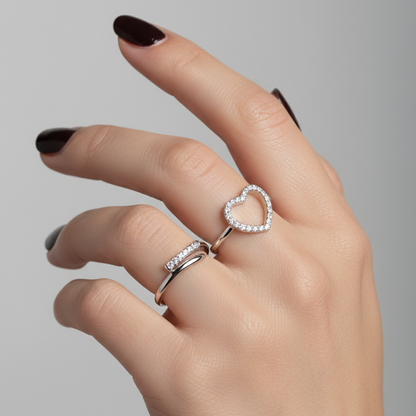 Hand wearing two silver rings on a plain background