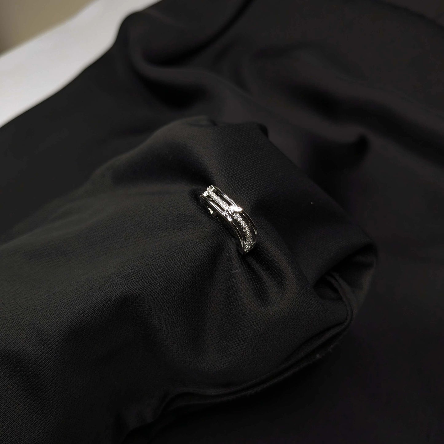 Close-up of a black fabric with a silver ring on a dark background