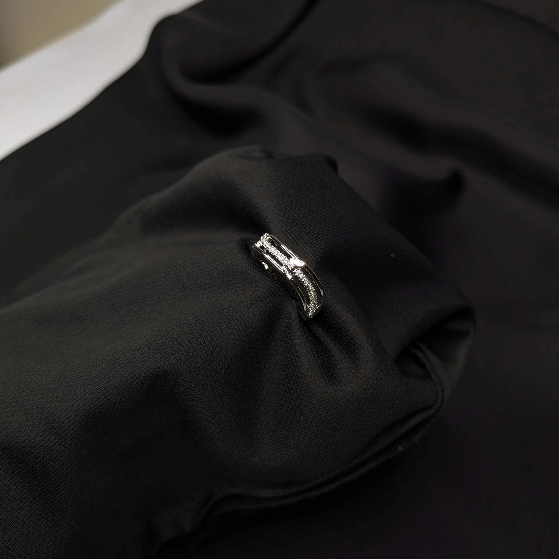 Close-up of a black fabric with a silver ring on a dark background